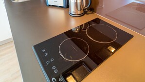 A modern kitchen with a built-in induction cooktop, a toaster, a kettle, and a sink.