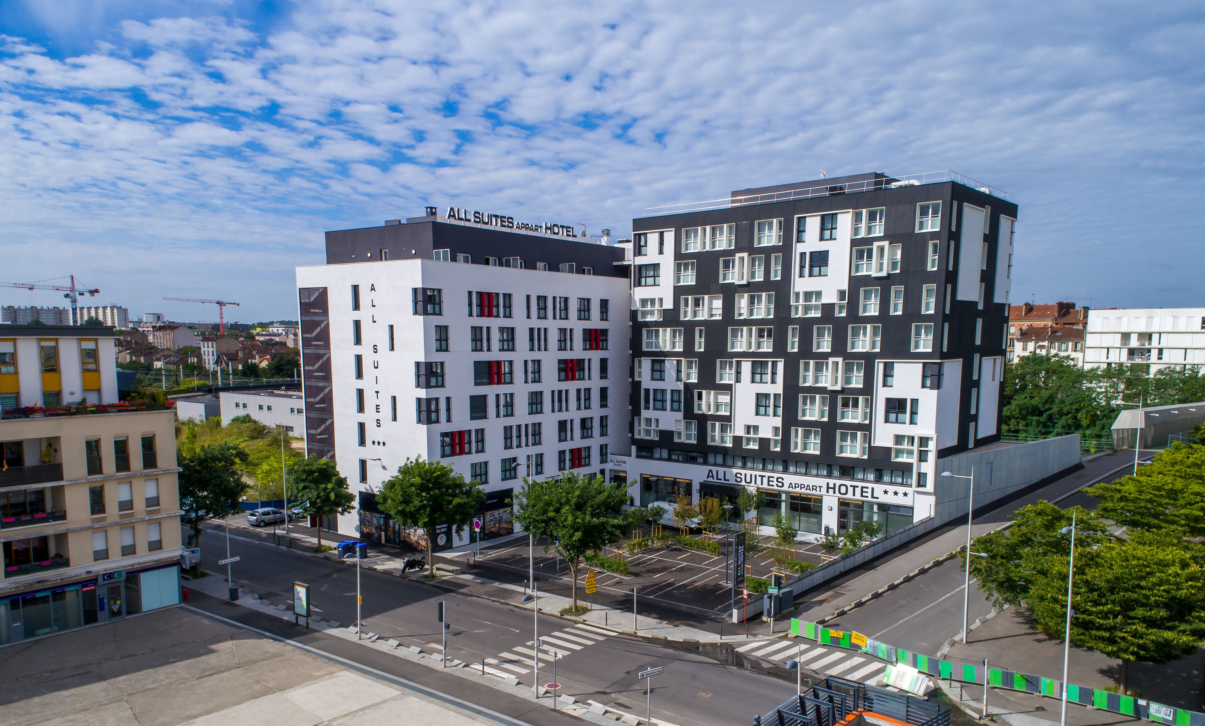 A modern hotel with multiple floors, large windows, and a prominent sign for All Suites Apartment Hotel.