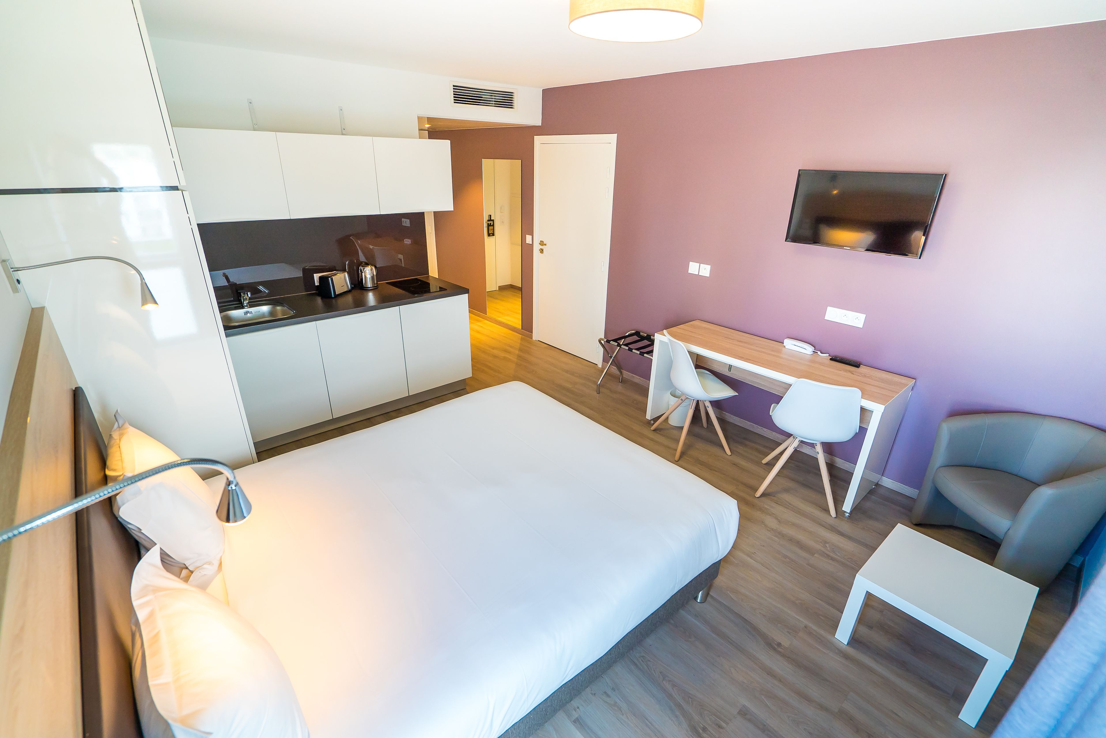 A compact room with a bed, a desk, a chair, and a TV.