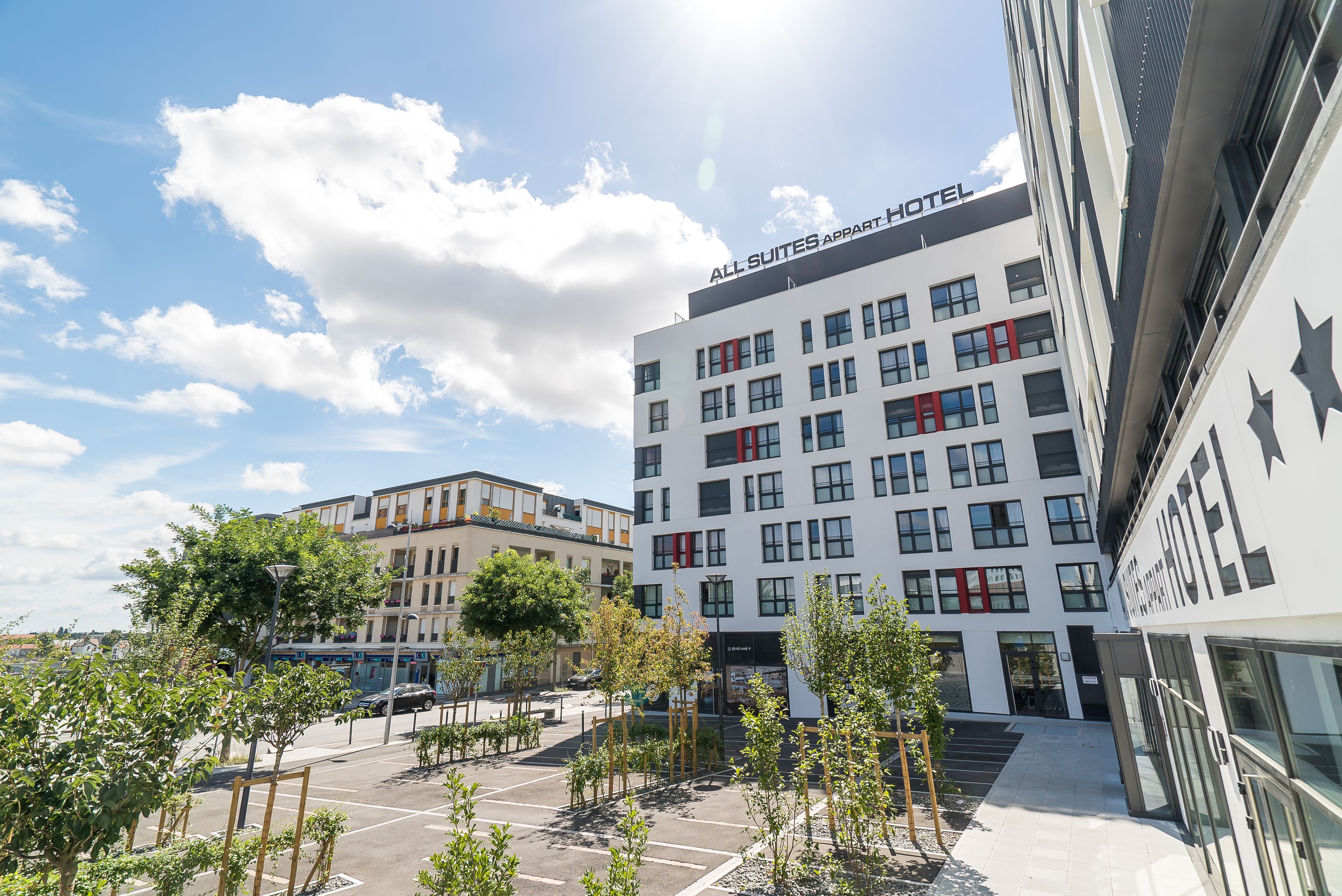 Un hotel moderno con fachada blanca, varios pisos y un letrero que dice "ALL SUITES APART HOTEL".