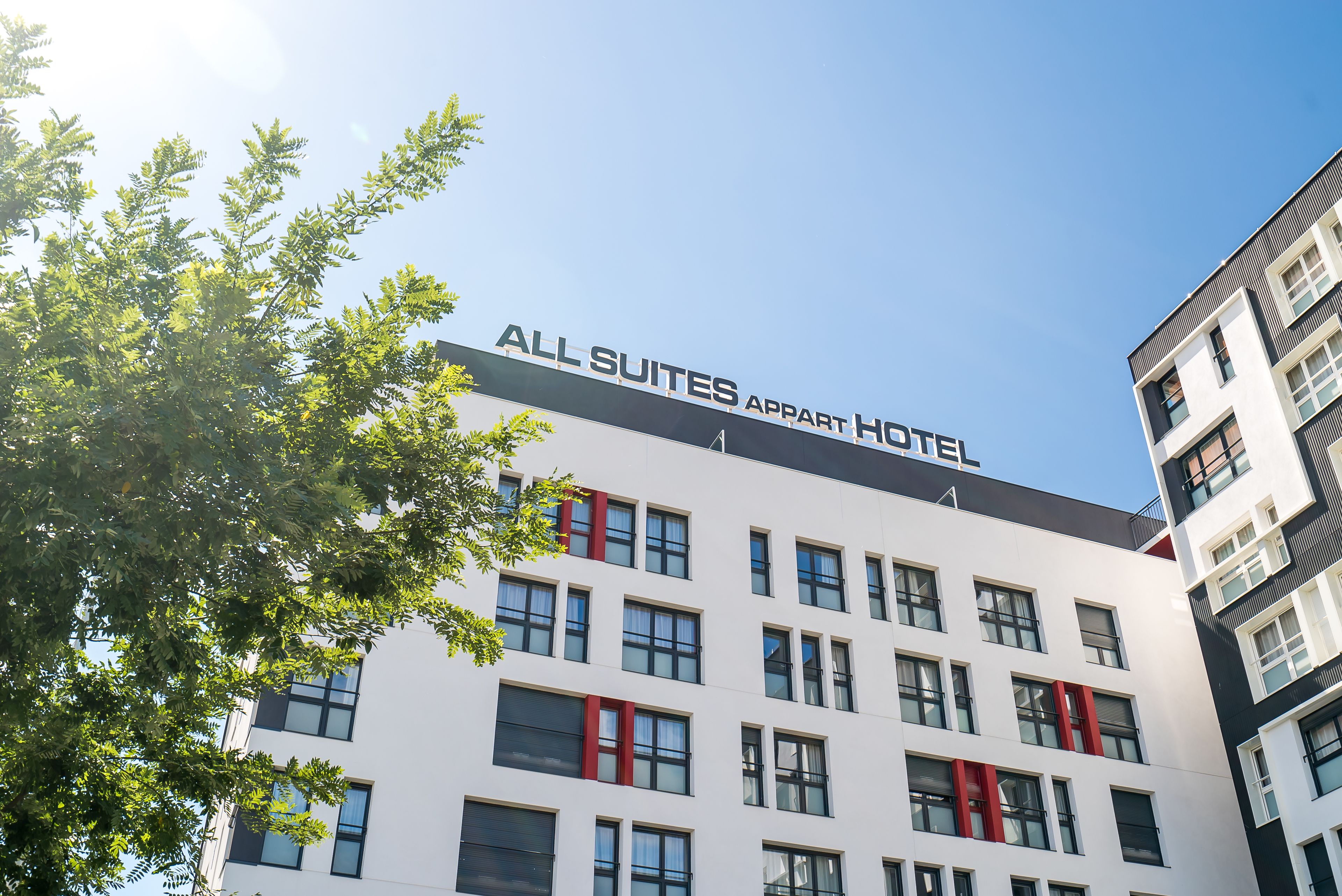 A modern building with the sign "ALL SUITES APART HOTEL" indicating a hotel with multiple suites.