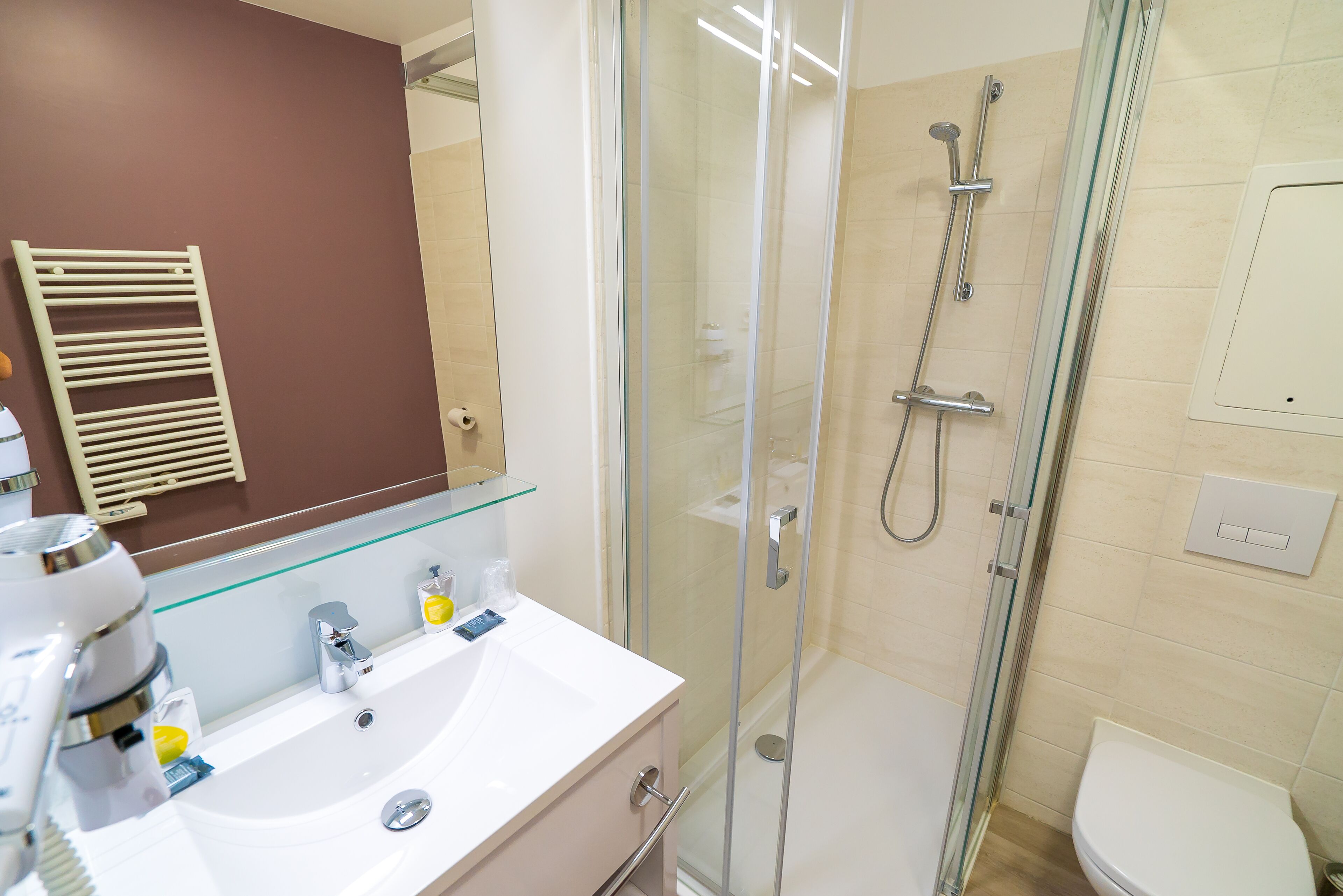A modern bathroom with a glass-enclosed shower, a white sink, and a mirror.