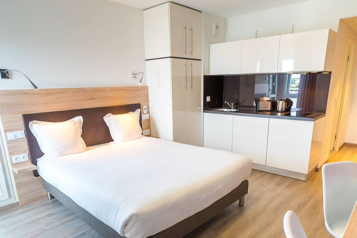 Une chambre d’hôtel moderne équipée d’un lit, d’une petite kitchenette et d’un coin repas.