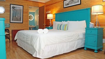 Une chambre d’hôtel avec un grand lit, deux tables de chevet avec des lampes, un plancher en bois et un panneau mural en bois.