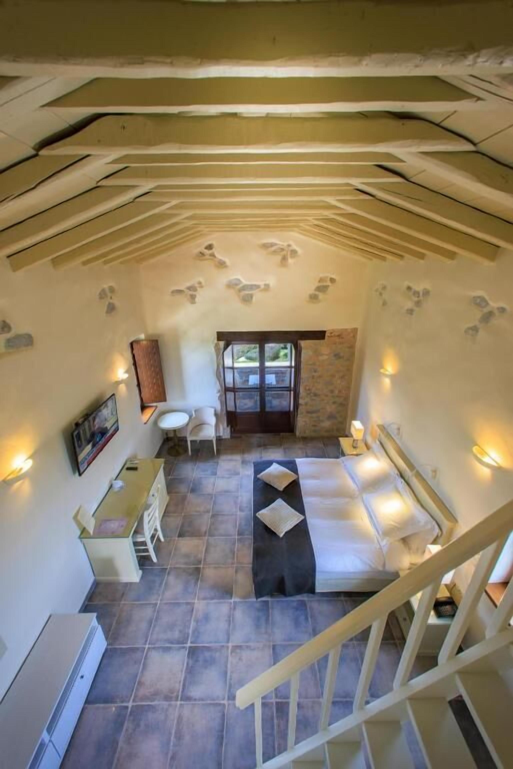 Una habitación acogedora con cama, una mesita y una silla. Se ve una escalera que sube a otro nivel.