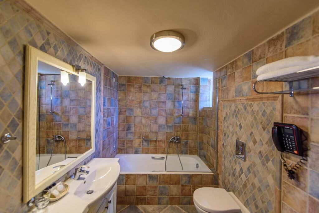 A bathroom with a bathtub, a toilet, a sink, and a mirror.