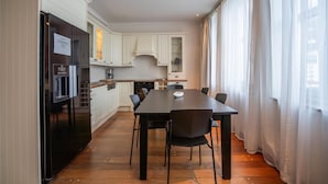 A modern kitchen with white cabinets, a black refrigerator, and a dining table with chairs. - Prize by Radisson, Xhibition Bergen City (Bergen)