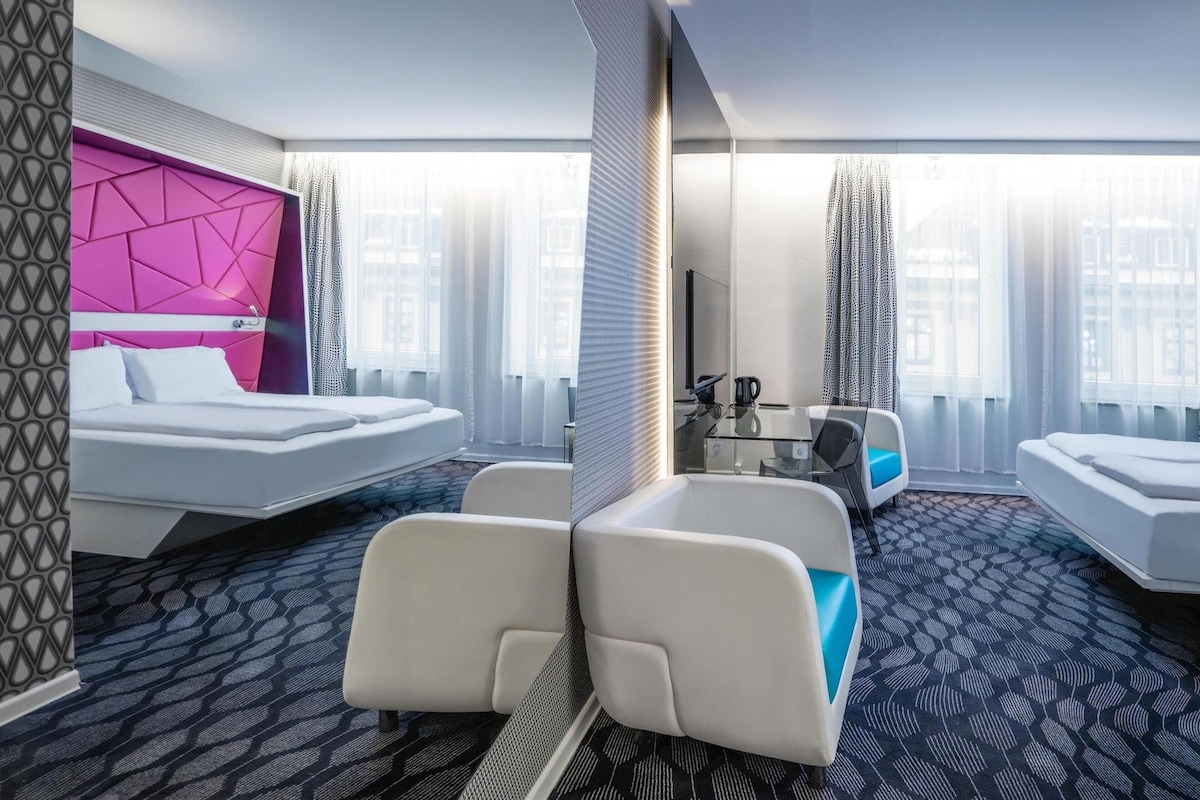 Una habitación de hotel con cama, escritorio y dos zonas de estar.