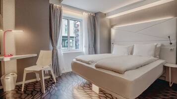 Una habitación de hotel moderna con una cama grande, un escritorio y una silla.