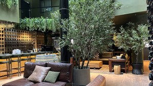 A modern lounge area with leather sofas, a bar with wine glasses, and potted plants.