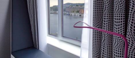 Una habitación con una ventana, un escritorio y una lámpara rosa.