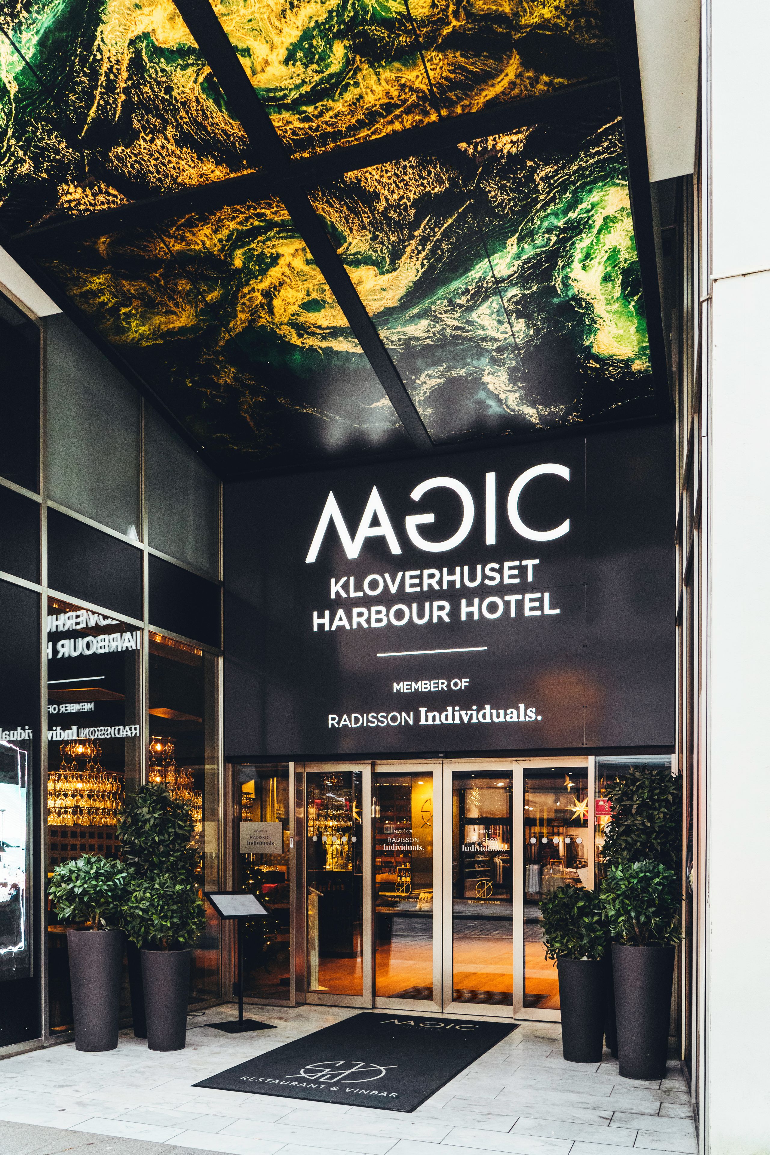 The exterior of the KLOVERHUSET HARBOUR HOTEL with a large digital display above the entrance.