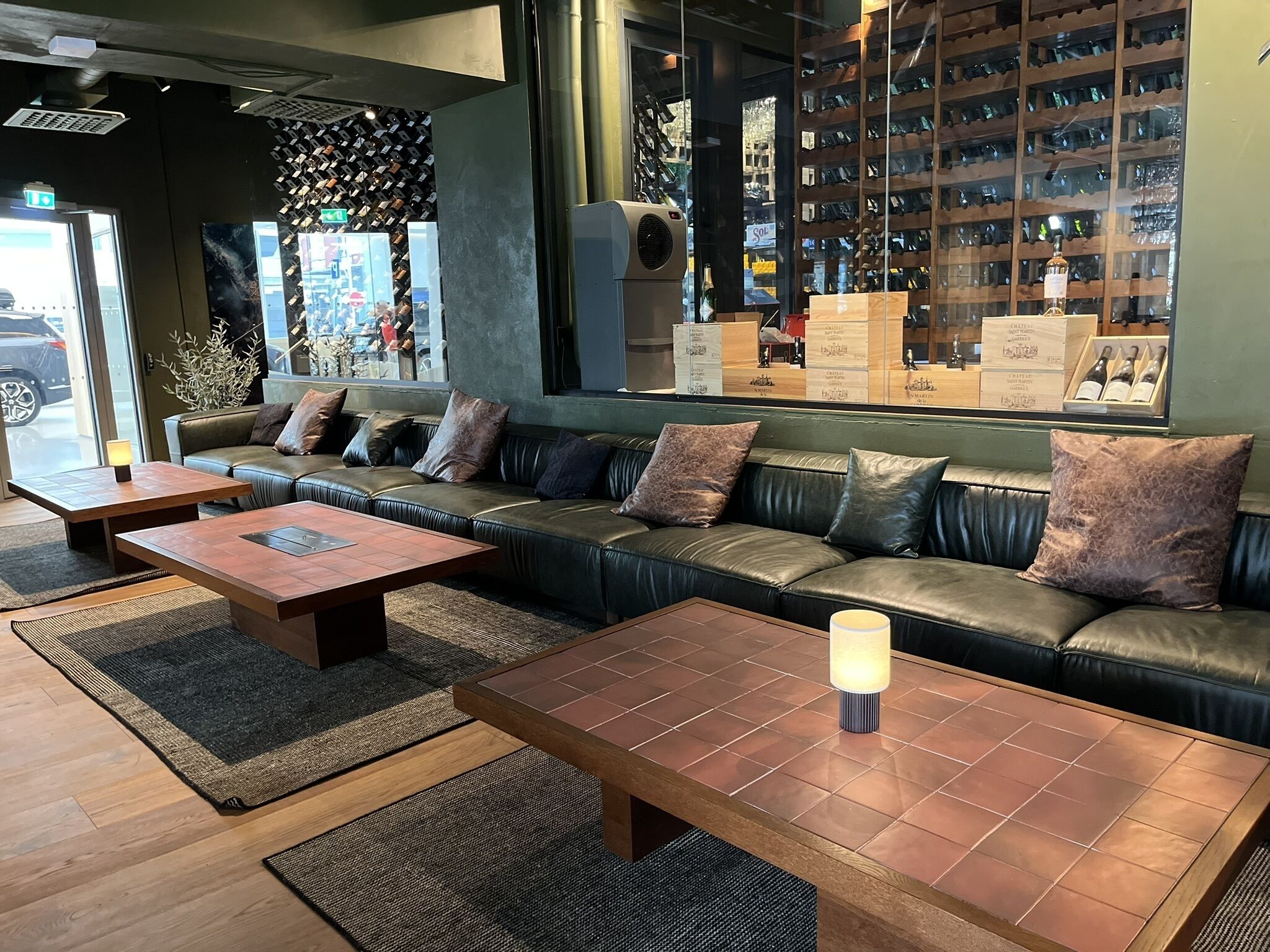 Un área de descanso moderna con sofás de cuero, mesas de madera y una exhibición de vinos.