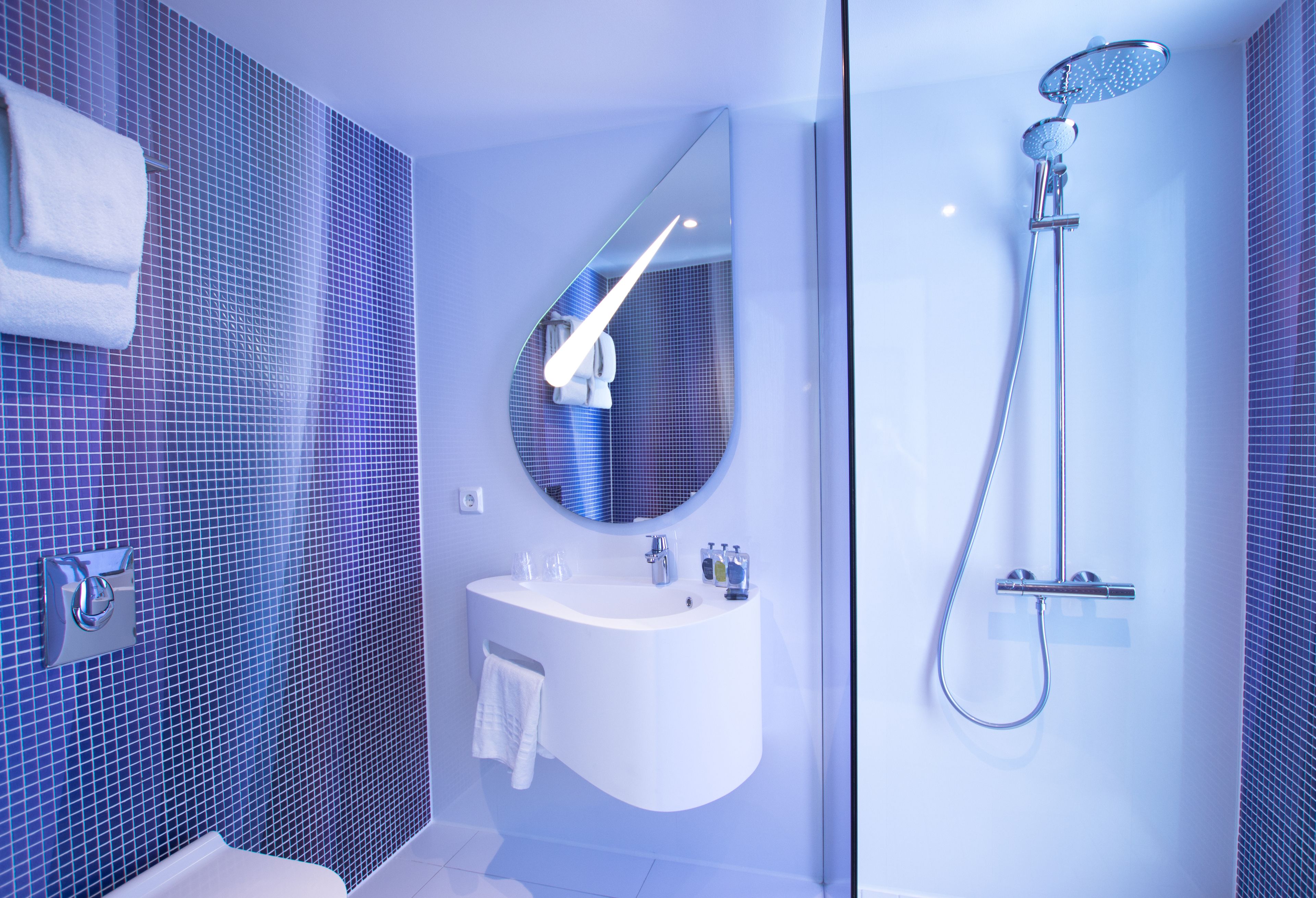 Une salle de bain moderne avec un grand miroir, un lavabo blanc et une douche.