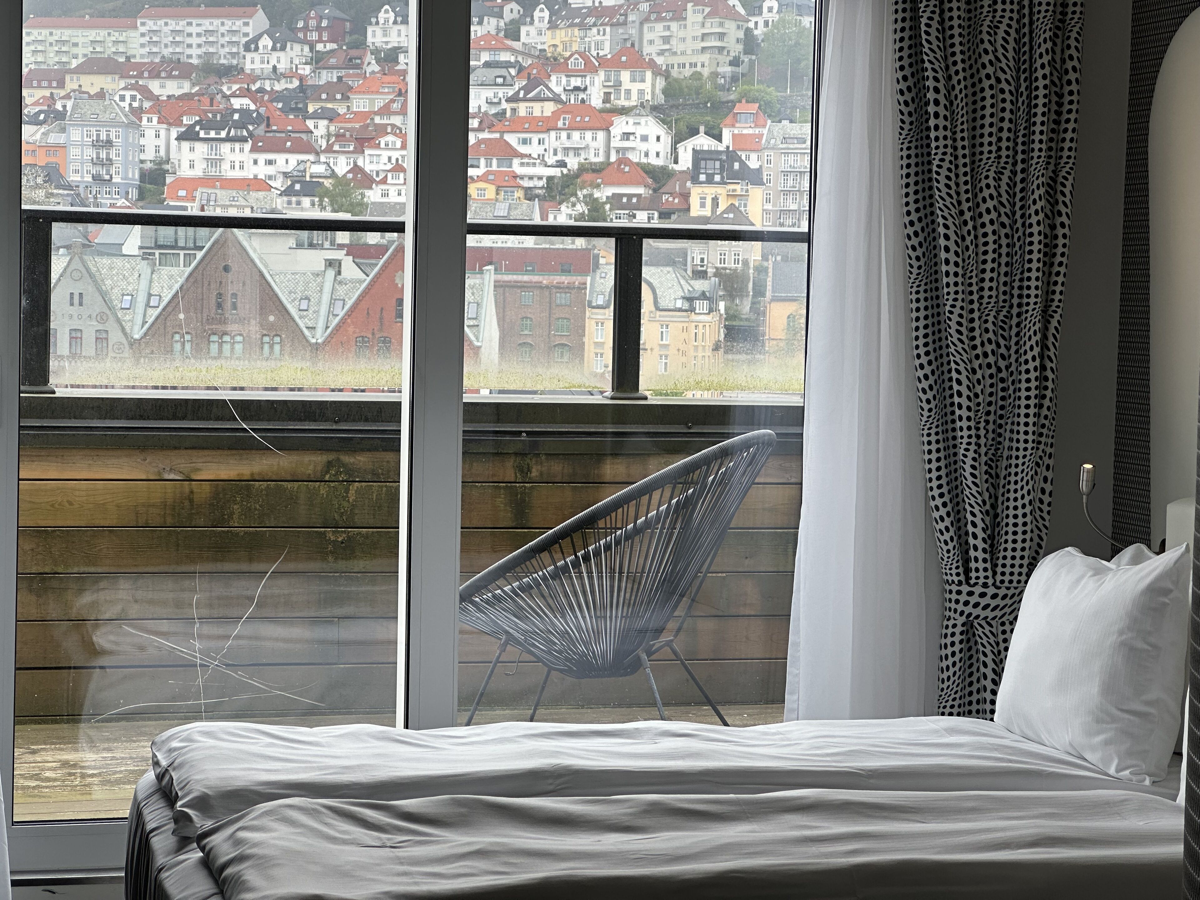 Un dormitorio con un ventanal grande que da a una zona residencial.