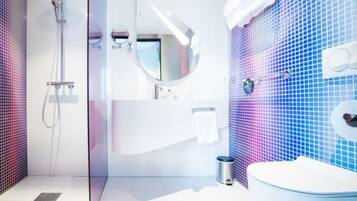 Un baño moderno con ducha de vidrio, lavamanos blanco y pared con azulejos azules.