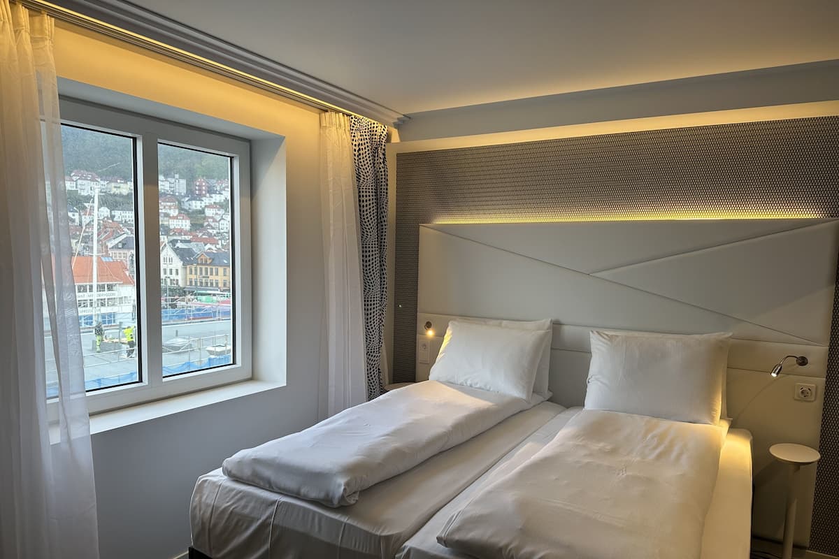 Une chambre d’hôtel avec un lit, une fenêtre et une vue sur les bâtiments environnants.