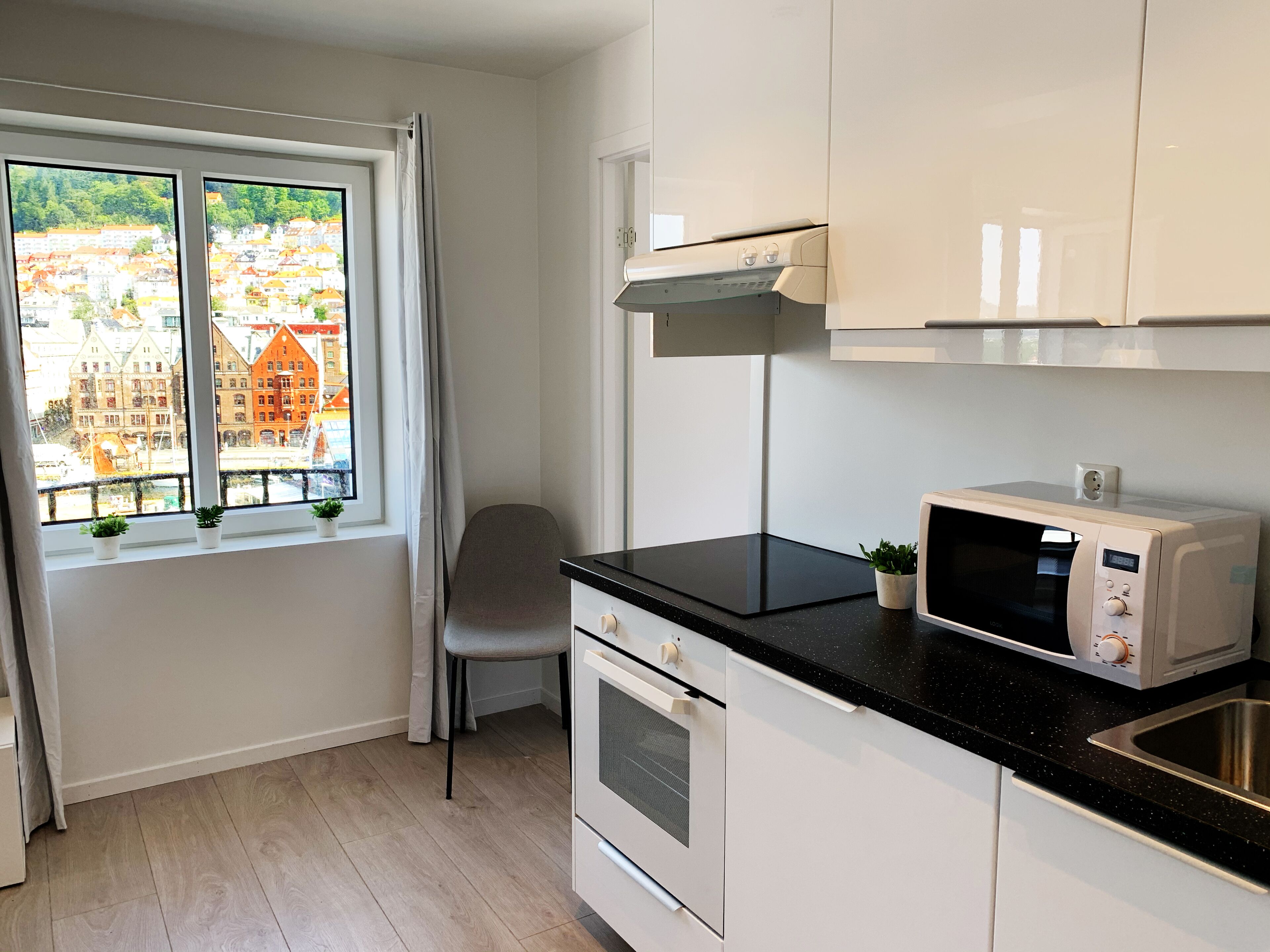 A modern kitchen with a window, a chair, and a microwave.