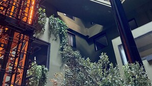 A multi-level atrium with a glass ceiling, metal framework, and indoor plants.