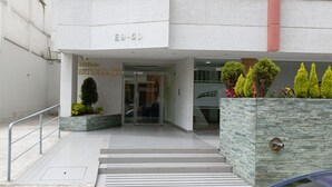 L’entrée de l’immeuble Estrellavi se distingue par sa façade moderne, une porte d’entrée en verre et un jardin en pierre agrémenté de plantes.