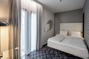 A modern hotel room with a large bed, a round mirror, and patterned curtains. - Magic Hotel Bergen City Center, a member of Radisson Individuals (Bergen)