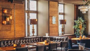 Un rincón de bar acogedor con asientos de cuero, mesas e iluminación ambiental.