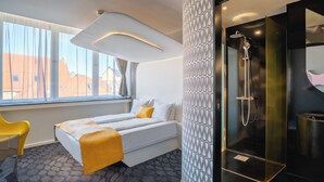 Una habitación de hotel moderna con una cama, ducha y vistas a edificios.
