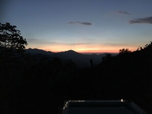 A view of a mountainous landscape at dusk with silhouettes of trees and mountains. - Finca Cafetera San Rafael (Santa Marta)