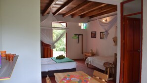 A cozy room with two beds, a wooden table, and a window with a mosquito net. - Finca Cafetera San Rafael (Santa Marta)
