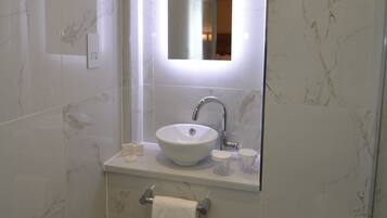 Ein modernes Badezimmer mit Marmorfliesen, integriertem Waschbecken, Spiegel und Handtuchhalter.