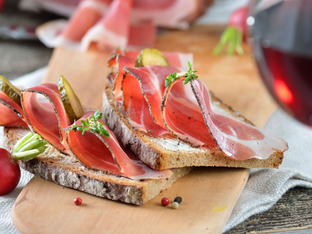 Slices of bread with smoked salmon and pickles on a wooden board.