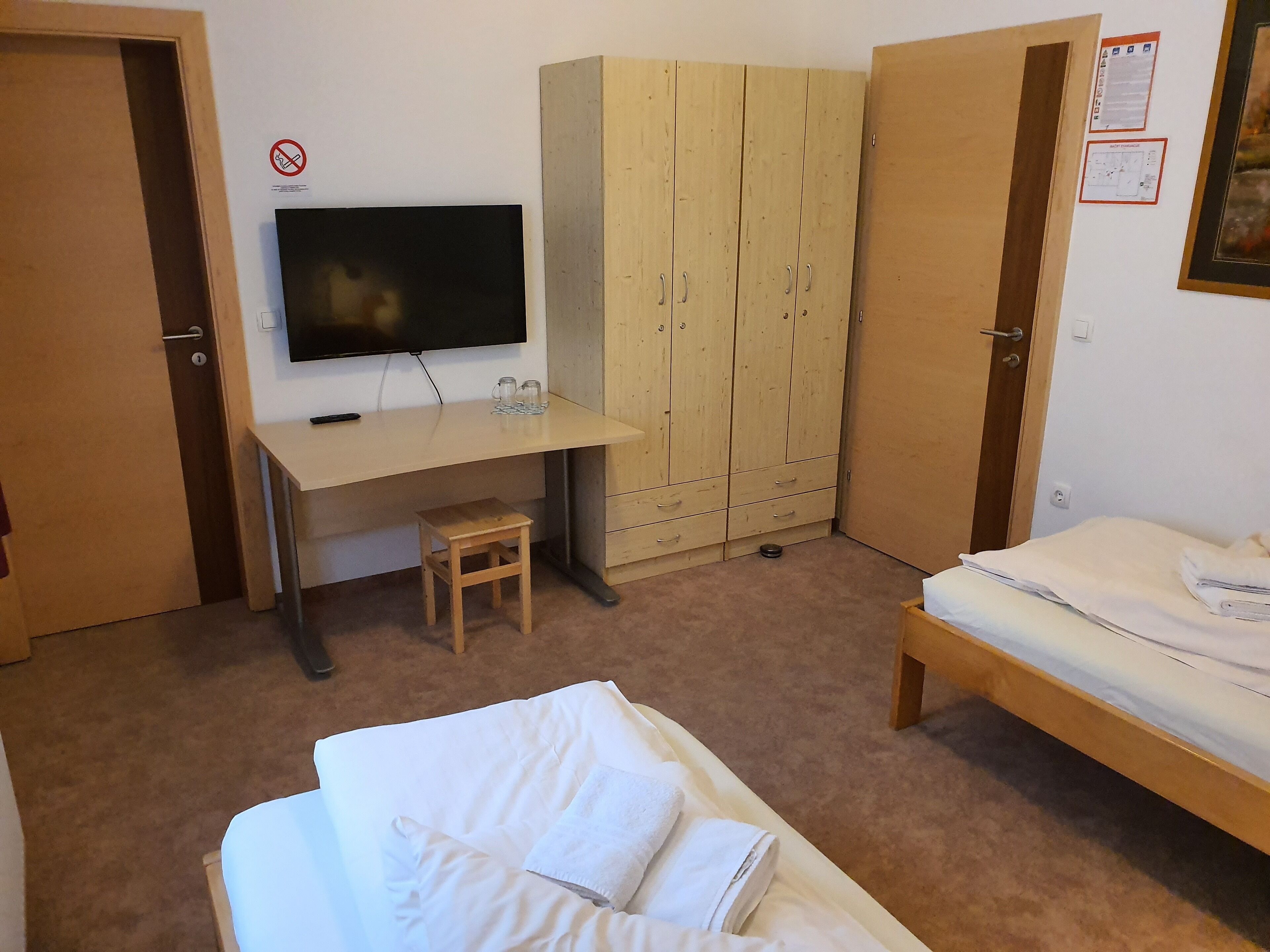 Un dormitorio con cama, escritorio, televisor y armario.