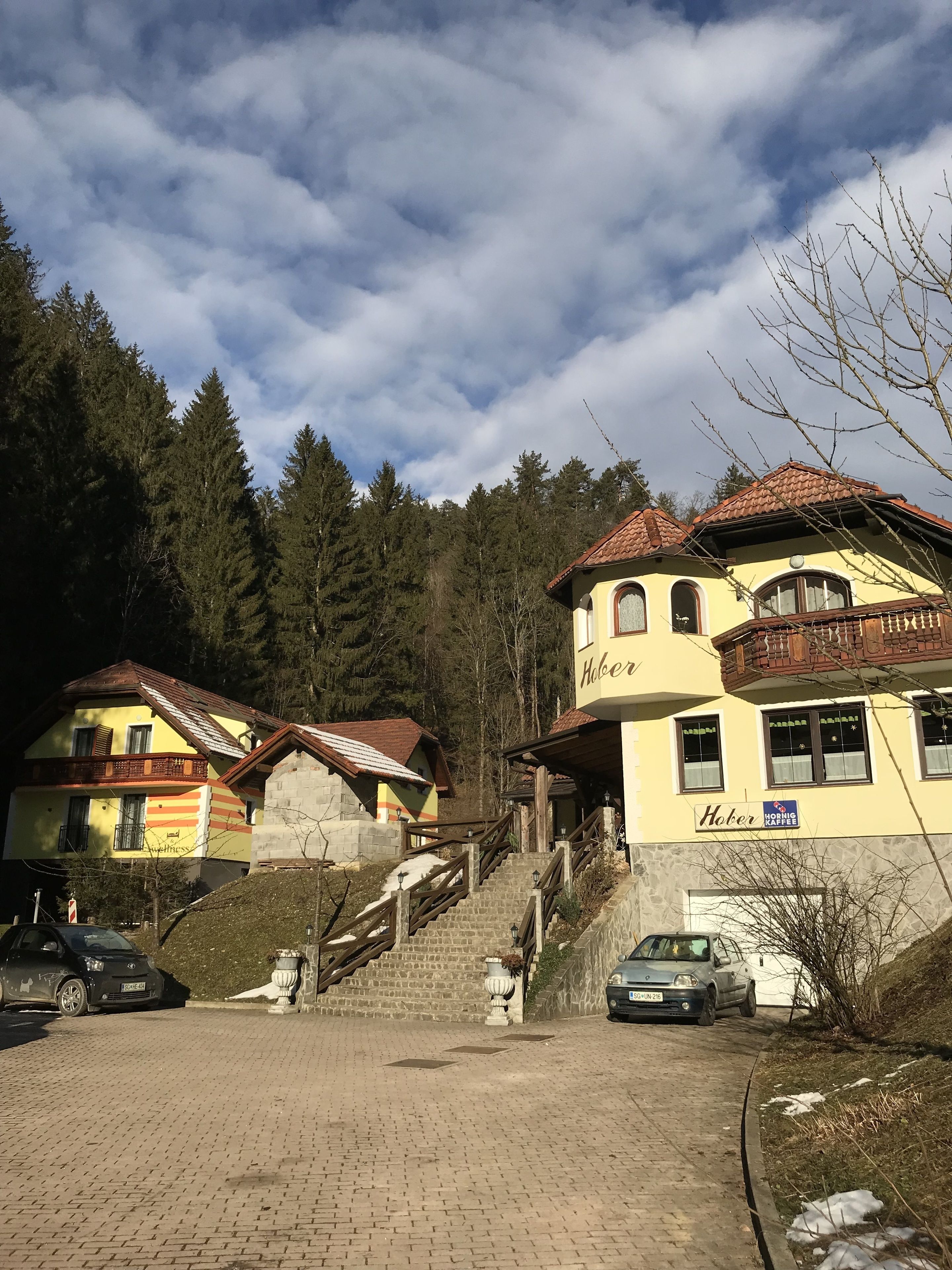 A hotel with a yellow facade, wooden balconies, and a sign for 'Hober'.