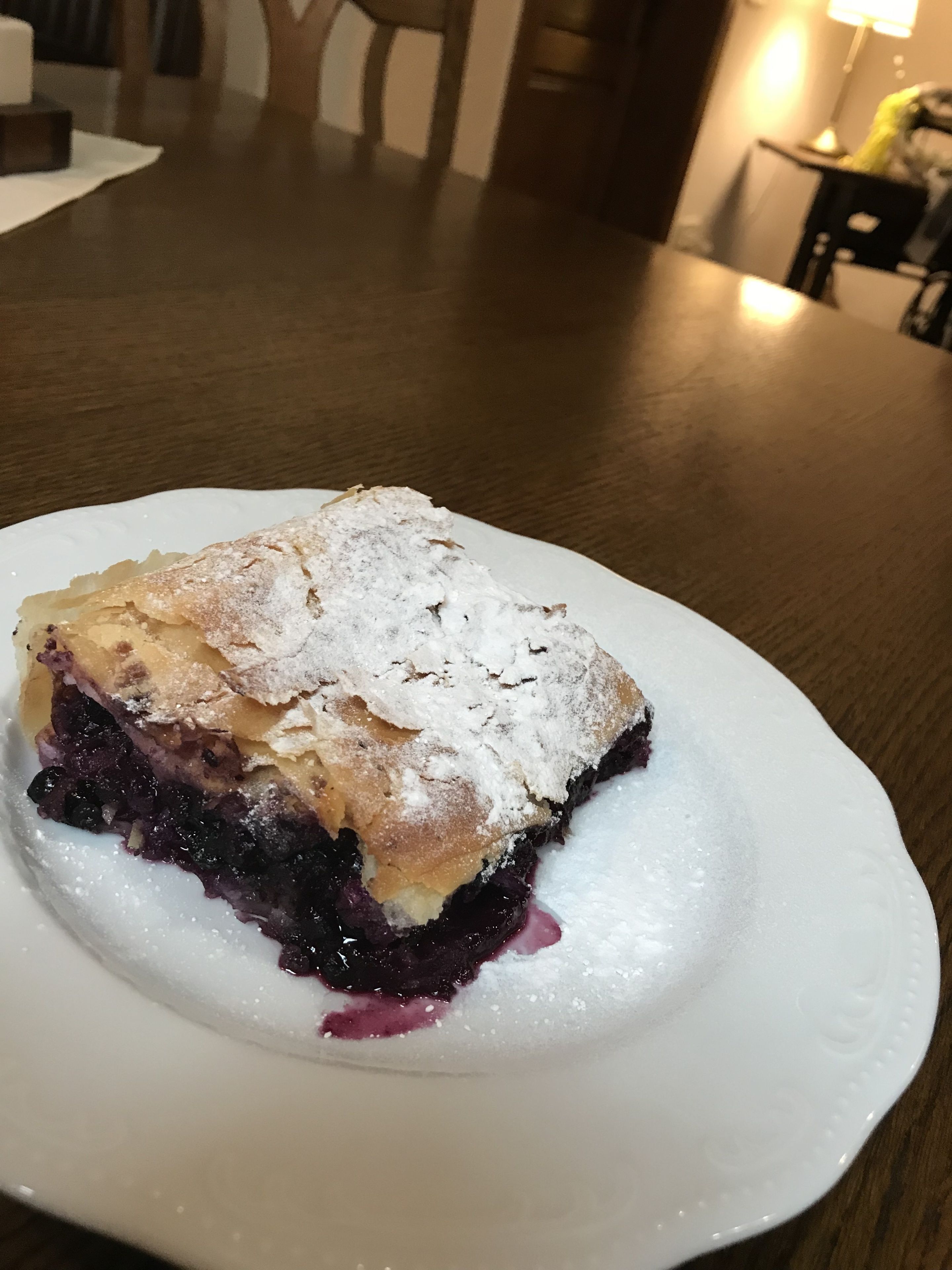 Uma fatia de torta de mirtilo em um prato branco.