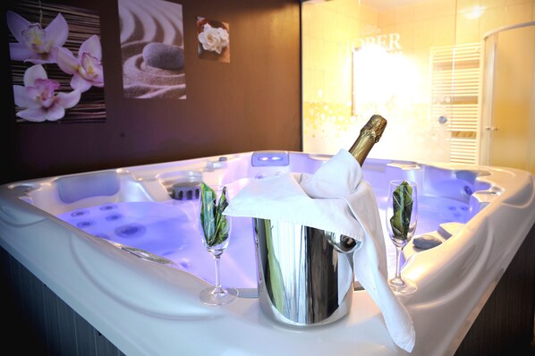 A hot tub with a champagne bottle, two glasses, and a napkin.