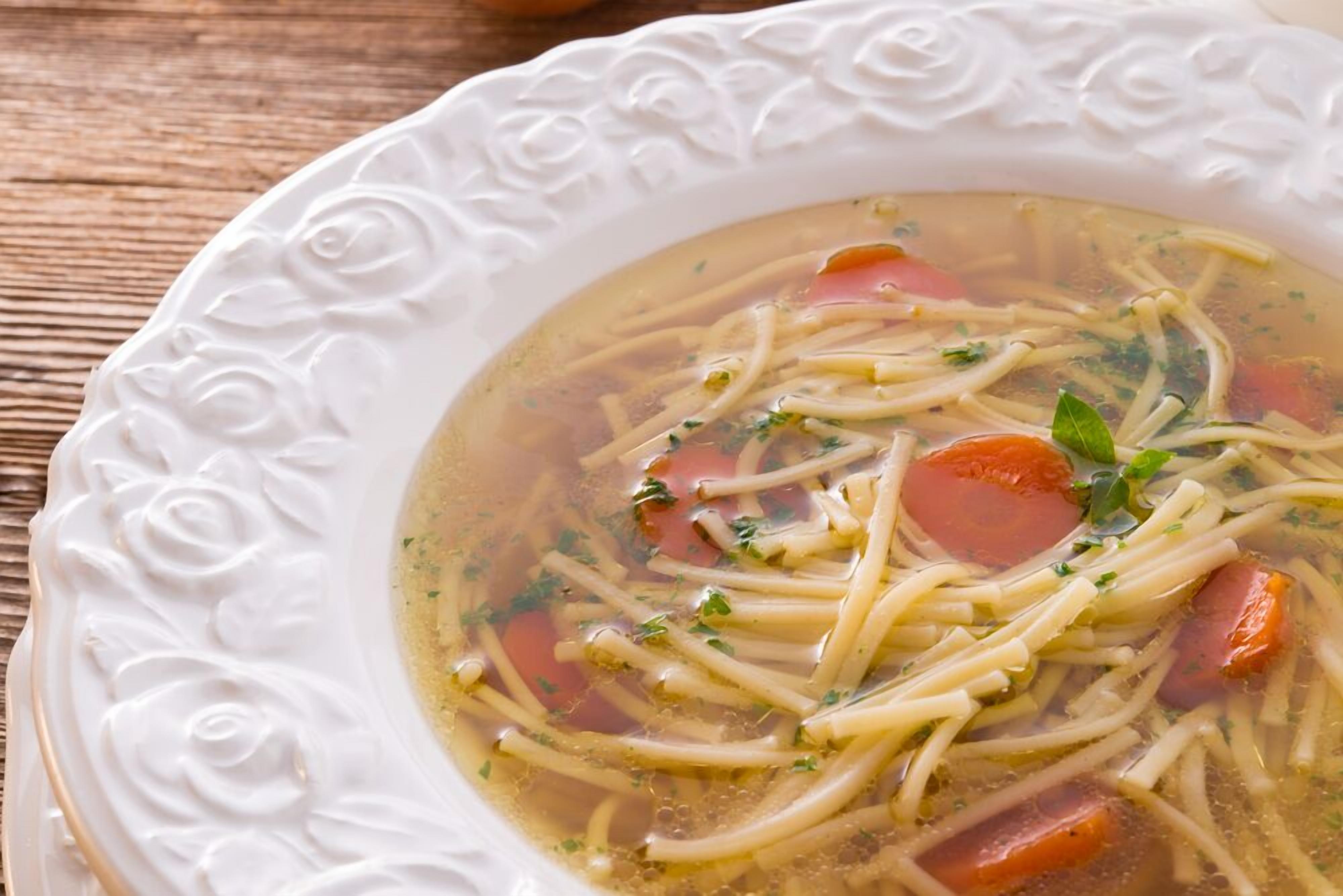 Un tazón de sopa con fideos y verduras.