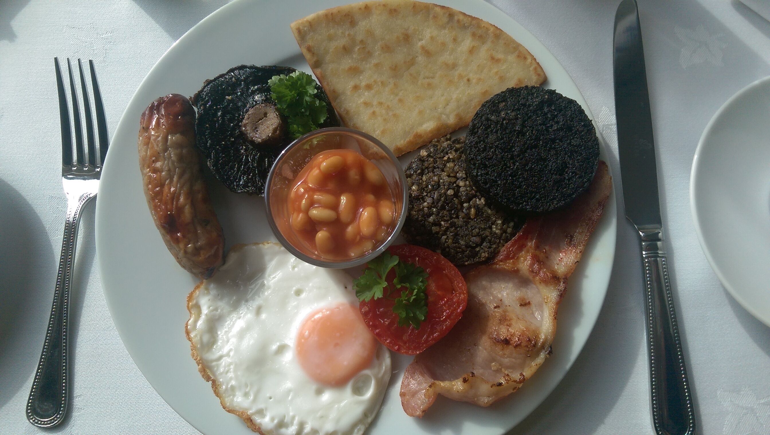 Plat de menjar per esmorzar amb ous, botifarreta, botifarra negra, fesols cuits i torrades.