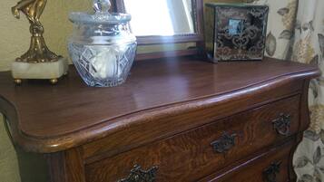 Un aparador de madera con cajones y tiradores ornamentales, un tarro de cristal con tapa, y una pequeña caja decorativa.