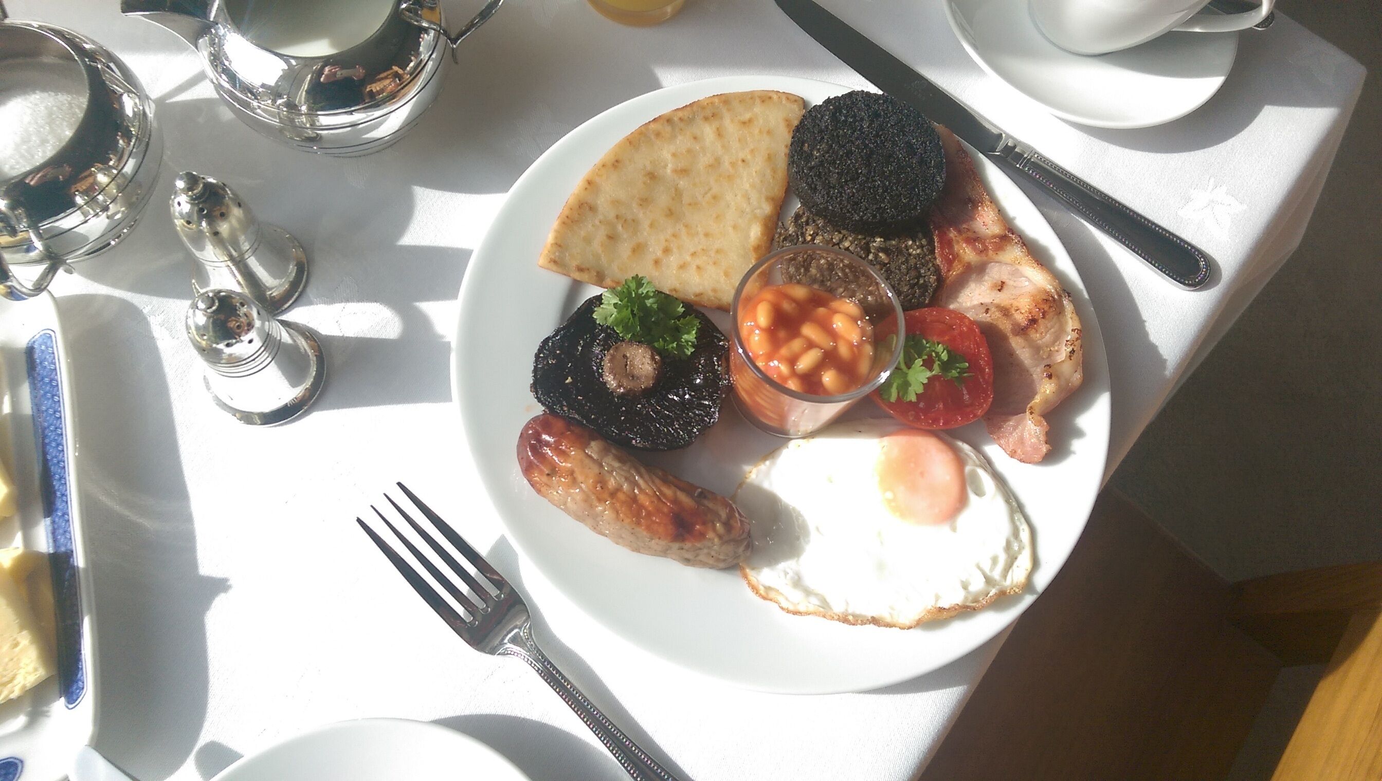 A breakfast plate with eggs, sausages, mushrooms, beans, and a slice of toast.