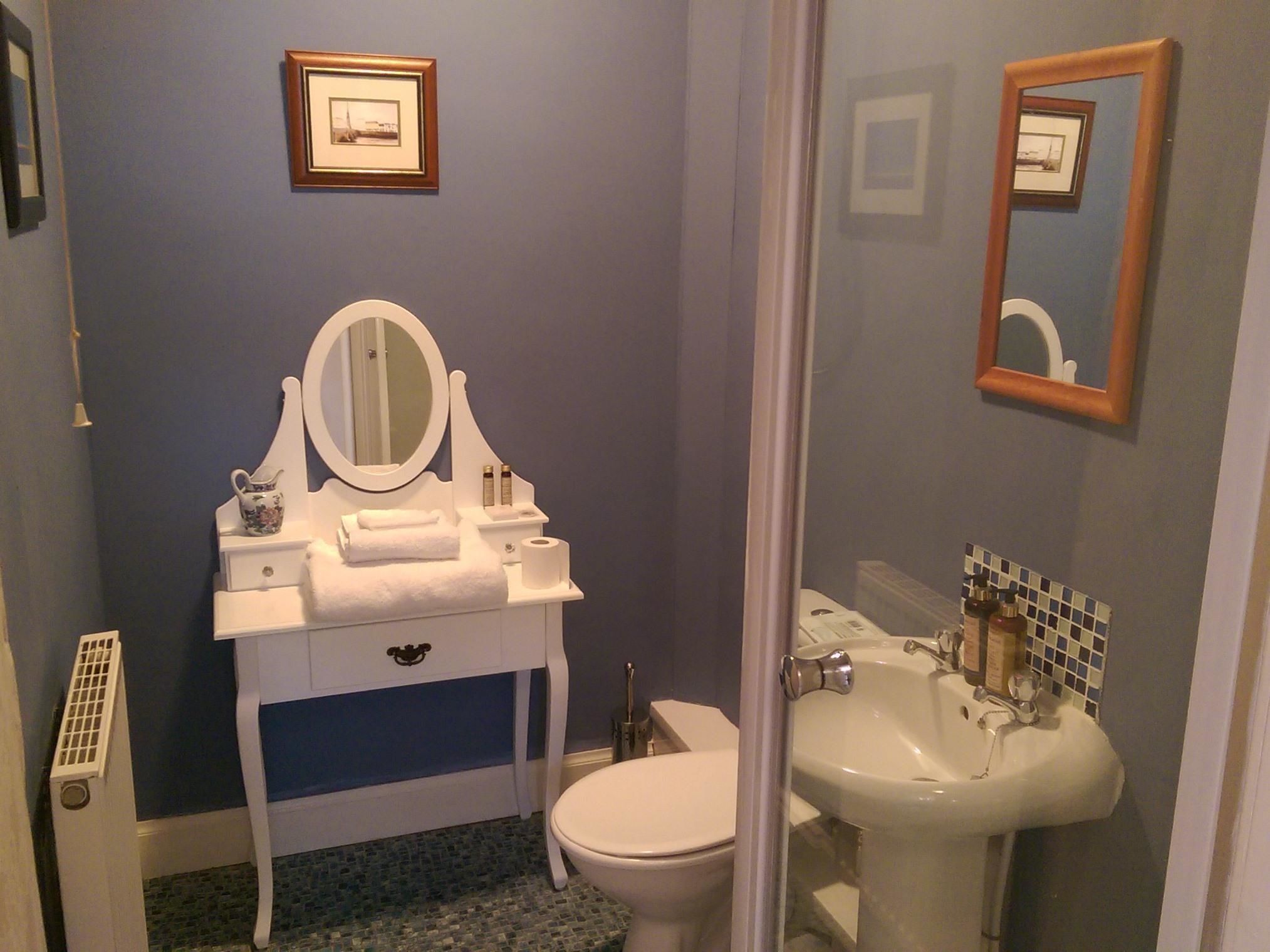 Un bagno con un mobile lavabo bianco, uno specchio, un water e un lavandino.
