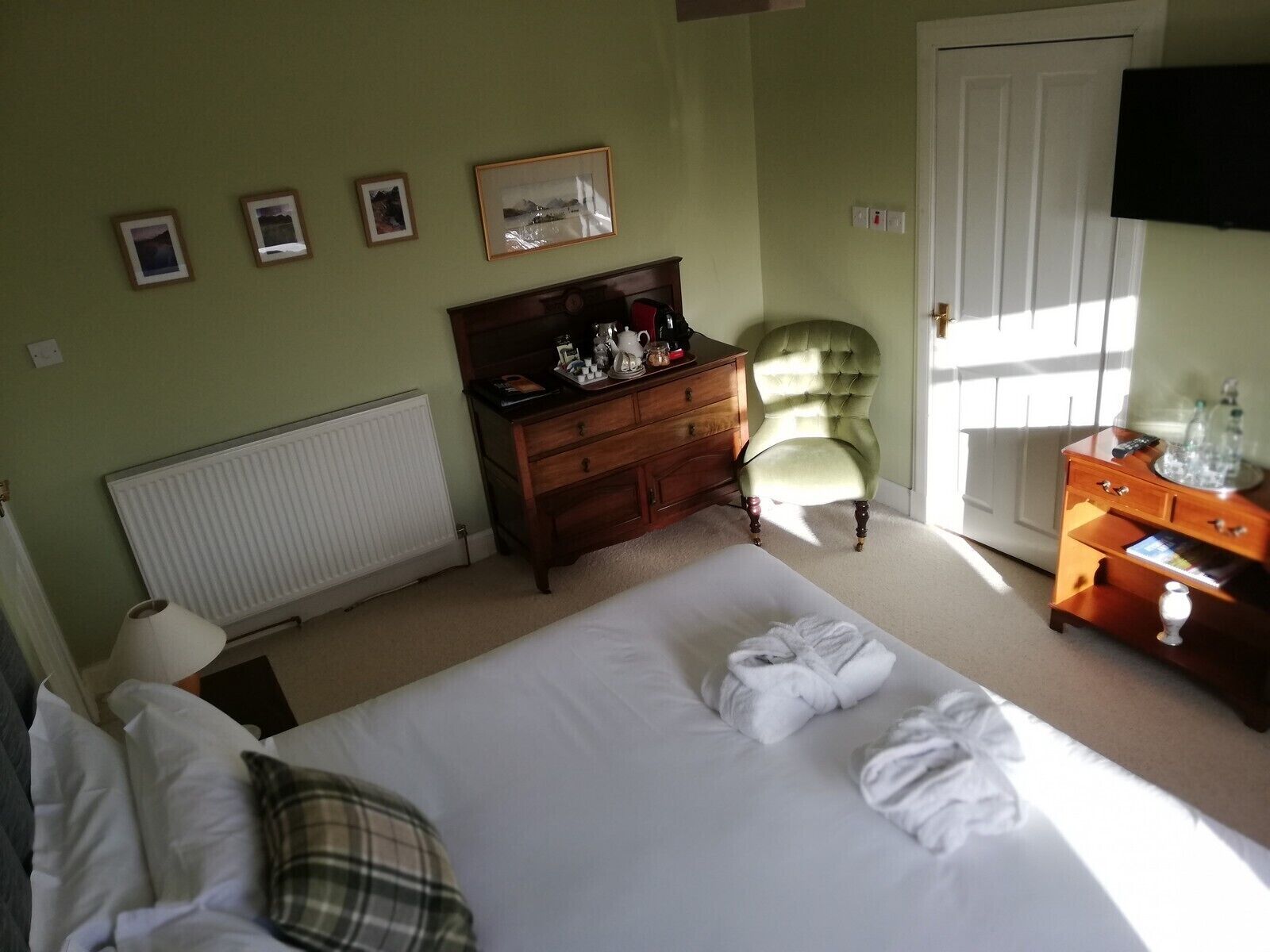 Ein Schlafzimmer mit Bett, Kommode, Stuhl und Heizkörper.
