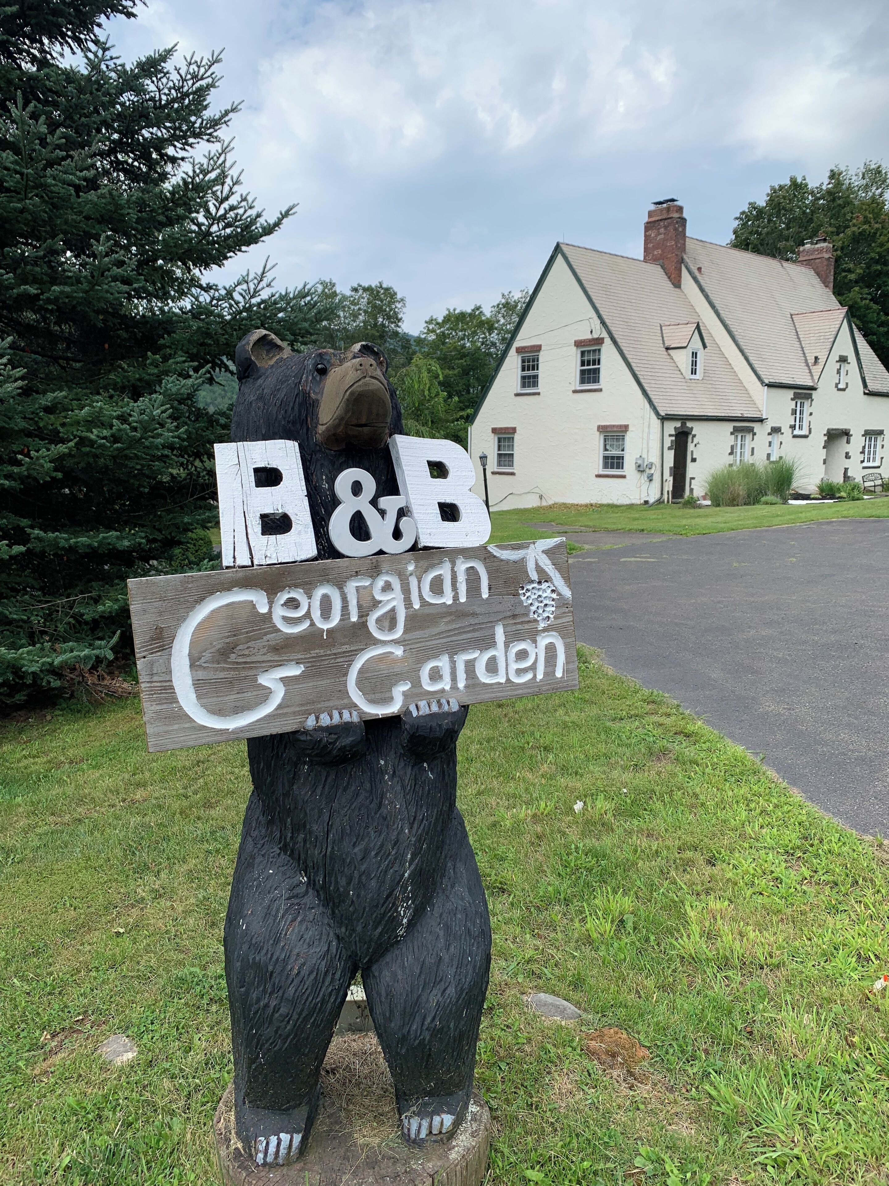 Una estatua de madera de un oso sosteniendo un letrero que dice "B&B Georgian Garden".