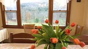 A table with a vase of orange tulips and a chocolate bundt cake. - Georgian Garden Inn (Windham)
