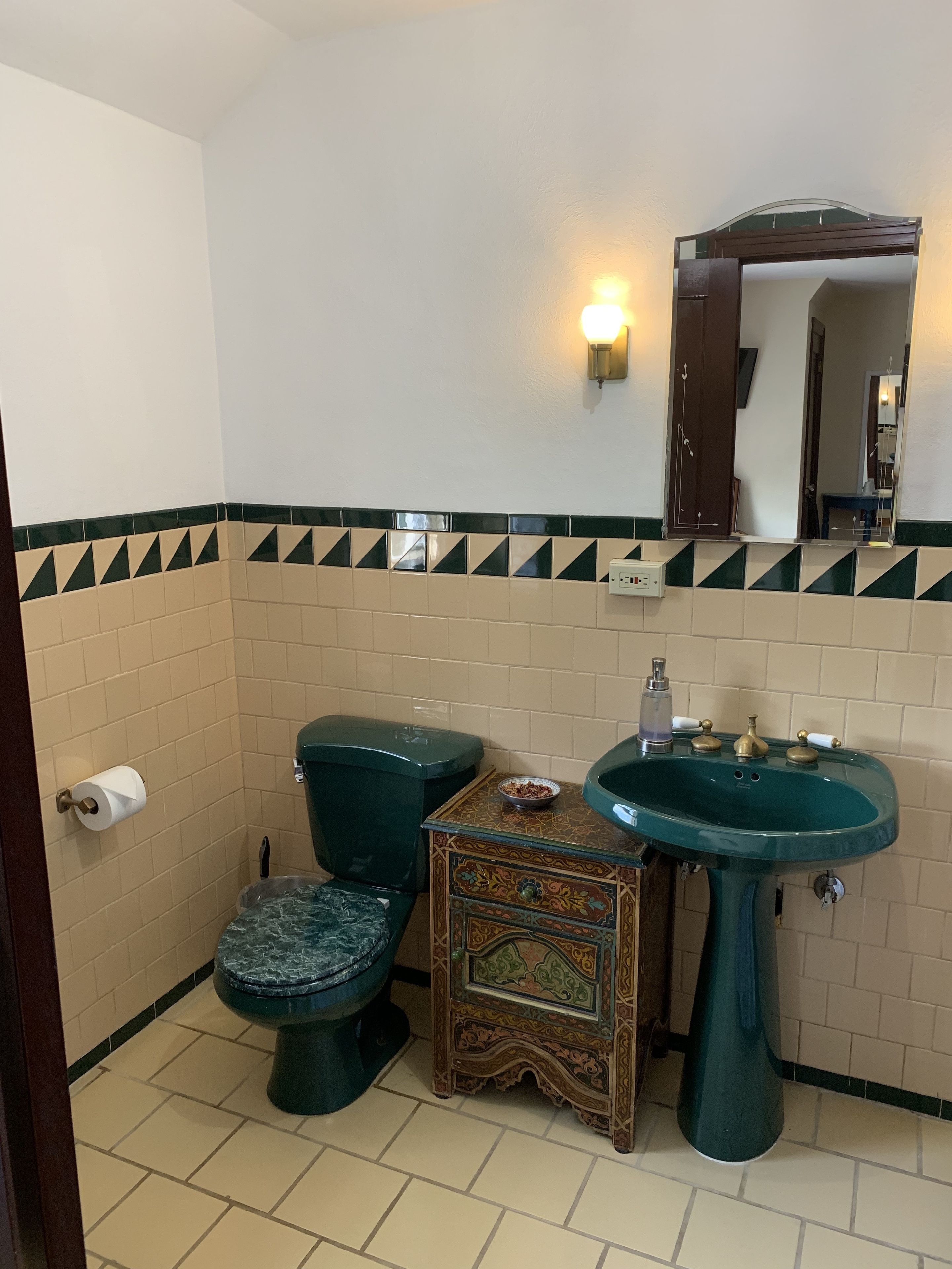 A bathroom with a toilet, sink, and decorative cabinet.