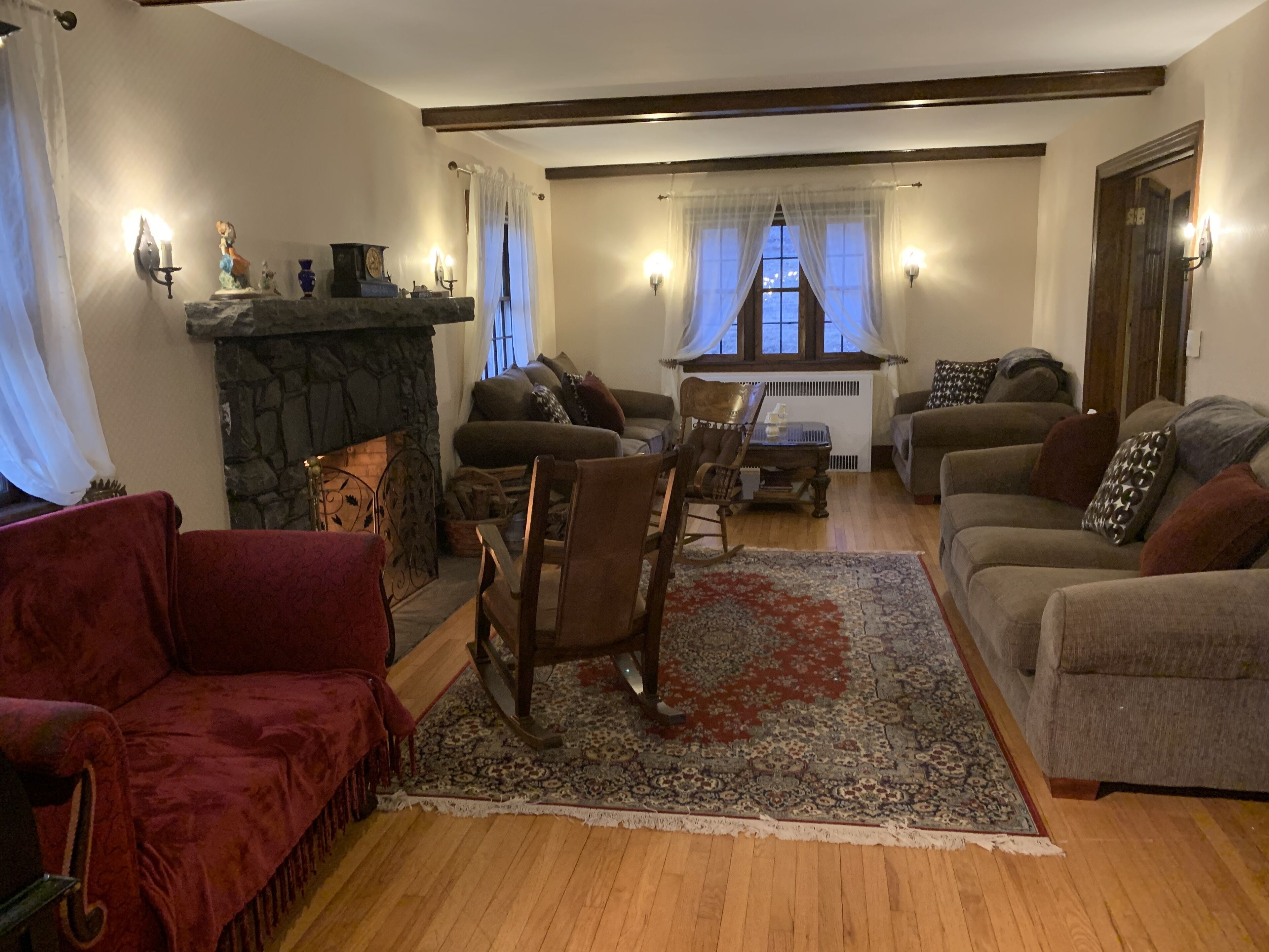 Een gezellige woonkamer met een stenen openhaard, houten vloeren en een combinatie van banken en fauteuils.