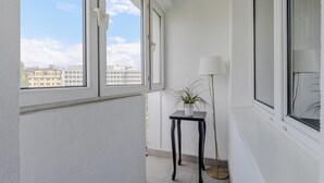 A balcony with a potted plant, a floor lamp, and a view of buildings through the windows. - ShortStayPoland Aleje Jerozolimskie B13 (Warsaw)