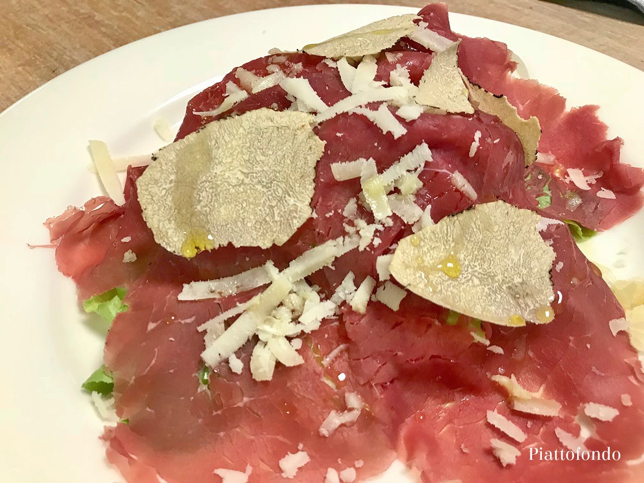 Ein Teller mit rohem Fleisch, geriebenem Käse und einer Garnitur.