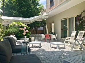 A patio area with a sofa, chairs, a table, and a potted plant. - Petit Hotel (Camaiore)