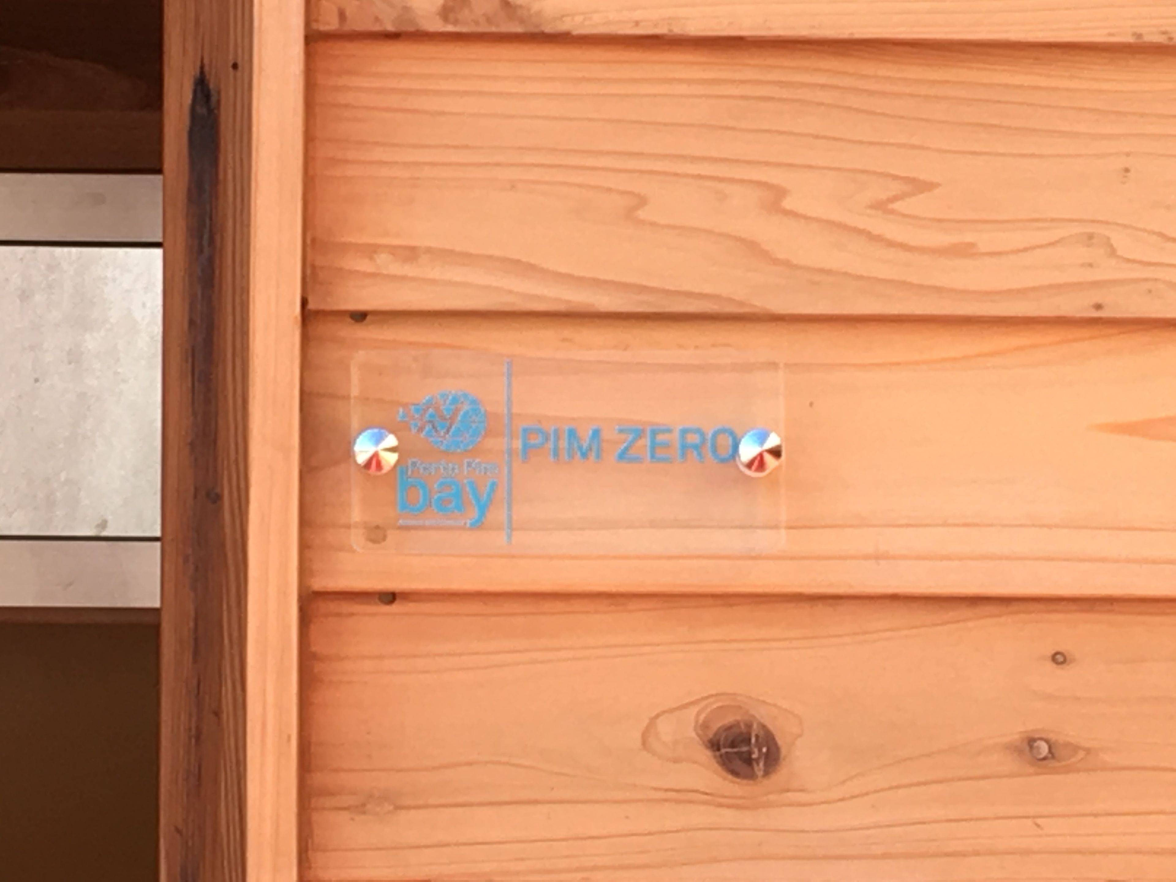 A wooden panel with a logo and text that reads "PIM ZERO bay".