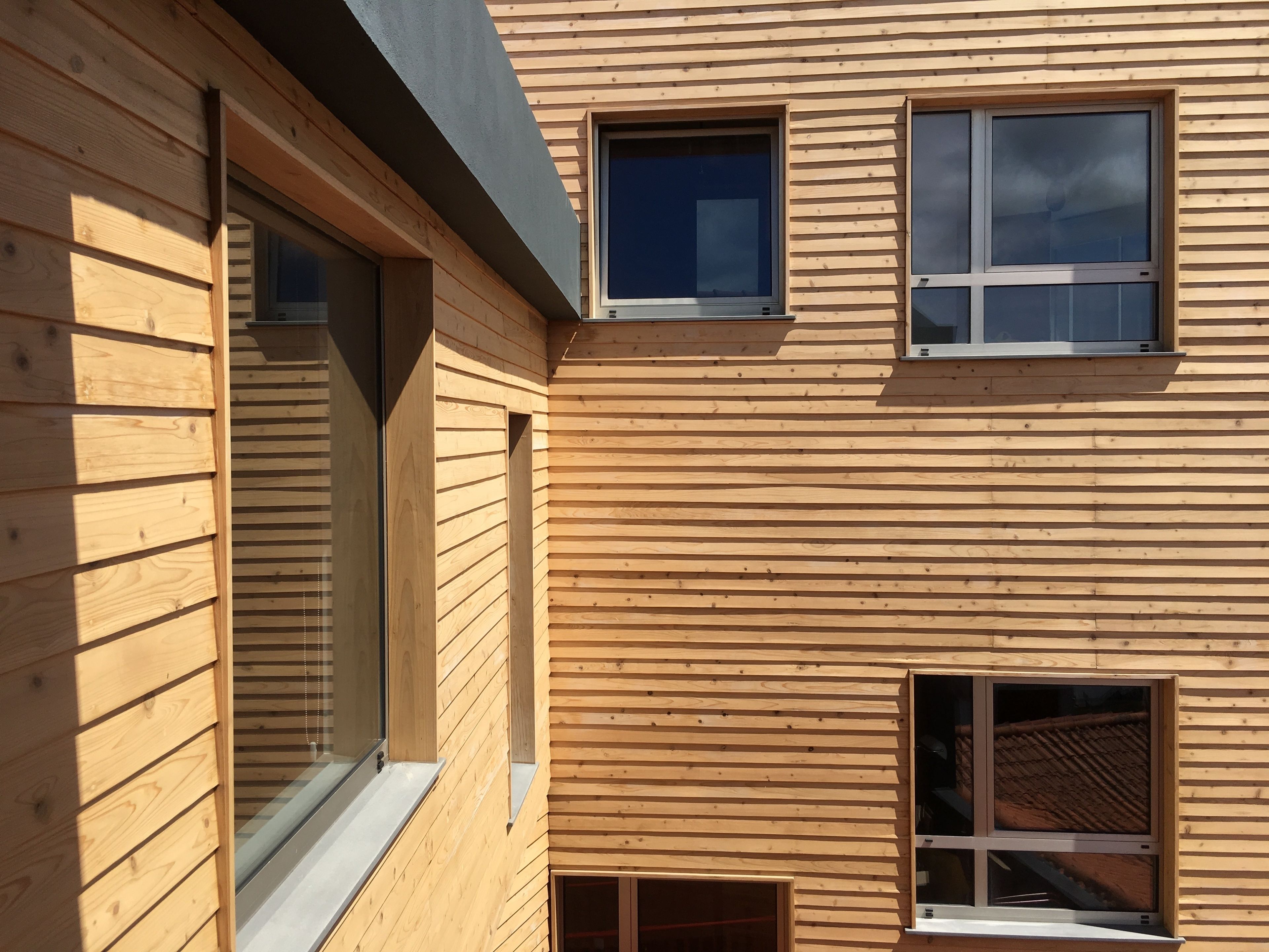 Un edificio de madera de varios pisos con ventanas amplias y techo inclinado.